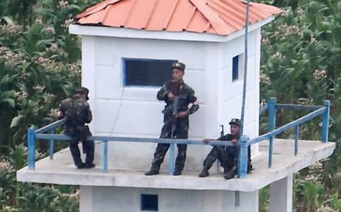 North Korean soldiers guard, seen from the Chinese border town of Tumen in eastern China's Jilin province - Credit: Kyodo News/AP