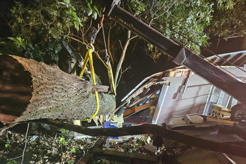 Crew from Eagle Towing removes a fallen tree that destroyed a cabin and trapped a counselor for 90 minutes Thursday, June 20, 2024, at Camp Ao-Wa-Kiya in Oceana County, Mich. Police said there were 14 people, including 12 girls, in the cabin. (Andrew Heykoop/Eagle Towing via AP)