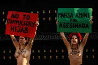 <p>SENSITIVE MATERIAL. THIS IMAGE MAY OFFEND OR DISTURB Activists from the women's rights group FEMEN hold signs, during a protest following the death of Mahsa Amini, outside the Embassy of Iran, in Madrid, Spain, September 23, 2022. REUTERS/Susana Vera</p> 
