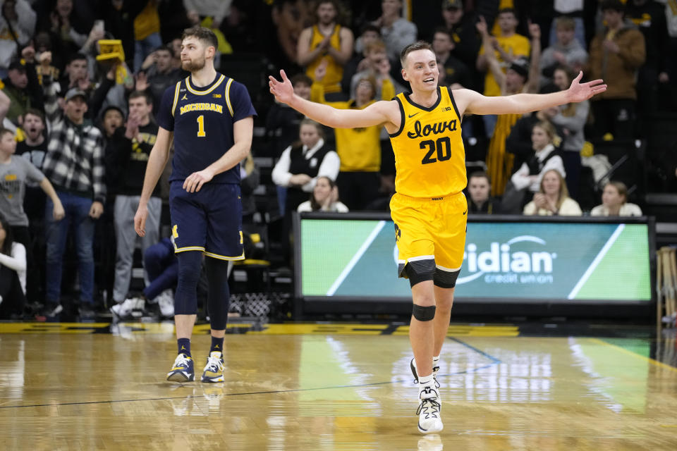 Iowa forward Payton Sandfort (20) celebrates in front of Michigan center Hunter Dickinson (1) at the end of an NCAA college basketball game, Thursday, Jan. 12, 2023, in Iowa City, Iowa. Iowa won 93-84 in overtime. (AP Photo/Charlie Neibergall)