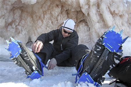 Jeff Neddo, from Eagle River, Wisconsin, tightens new crampons on his boots at the sea caves of the Apostle Islands National Lakeshore of Lake Superior near Cornucopia, Wisconsin February 14, 2014. REUTERS/Eric Miller