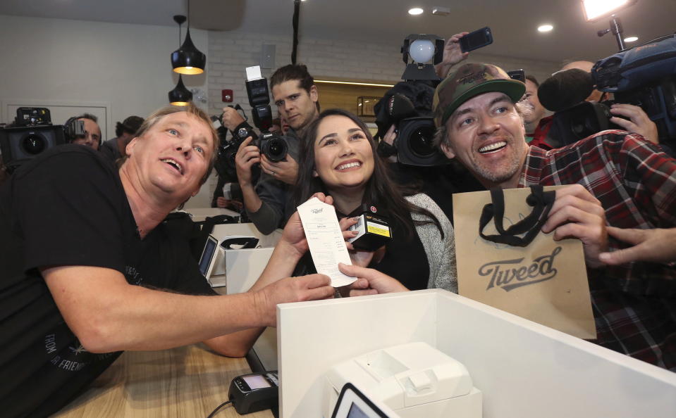 Canopy Growth CEO Bruce Linton, left to right, poses with the receipt for the first legal cannabis for recreation use sold in Canada to Nikki Rose and Ian Power at the Tweed shop on Water Street in St. John’s N.L. at 12:01 am NDT on Wednesday Oct. 17, 2018. (Paul Daly/The Canadian Press via AP)
