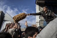 In this Dec. 4, 2016 file photo, an Iraqi man distributes potatoes to civilians in the Samah district of Mosul, Iraq. (AP Photo/Manu Brabo, File)