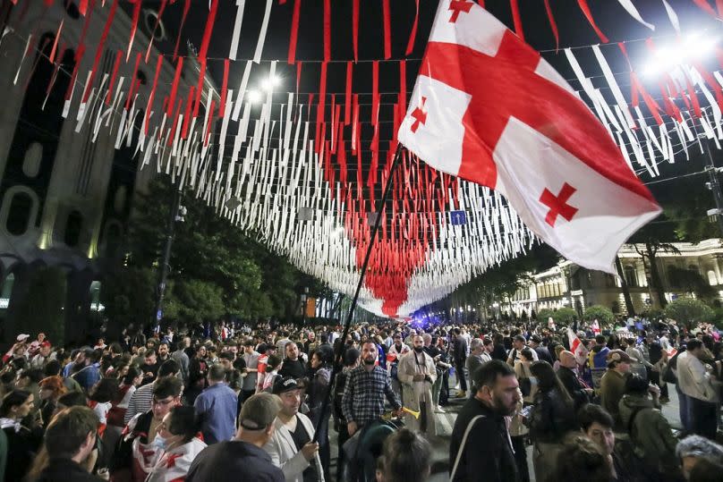 Des manifestants avec le drapeau géorgien devant le bâtiment du Parlement lors d'une manifestation de l'opposition contre le projet de loi sur l'influence étrangère à Tbilissi