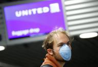 Passenger, standing at a ticket counter of U.S. carrier United Airlines, wears a protective mask at Frankfurt Airport