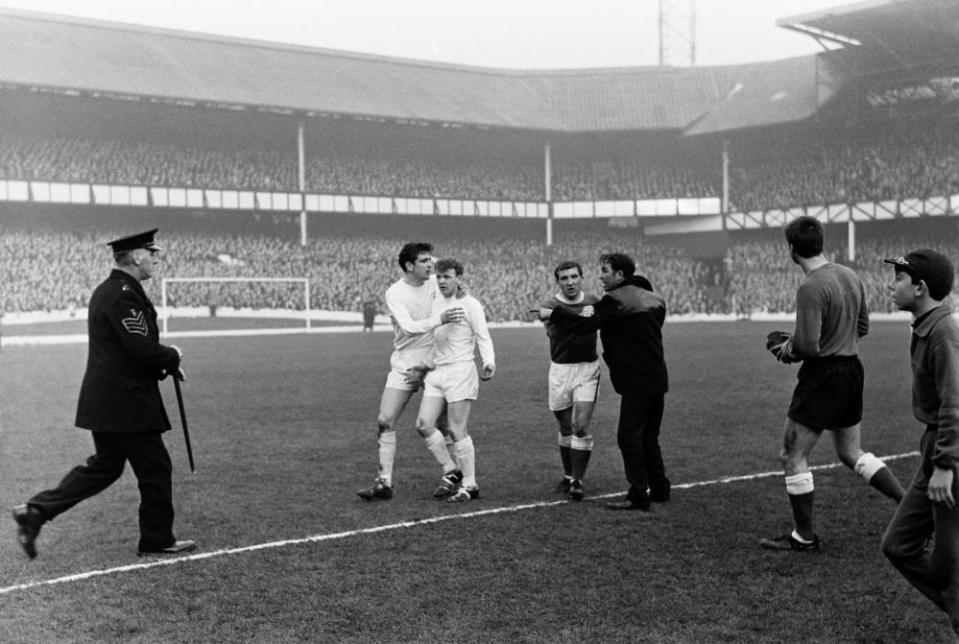 Billy Bremner is escorted off the pitch by Norman Hunter as a policeman runs onto the pitch to deal with a disgruntled and remonstrating Everton fan, who is held back by Everton’s Johnny Morrissey.