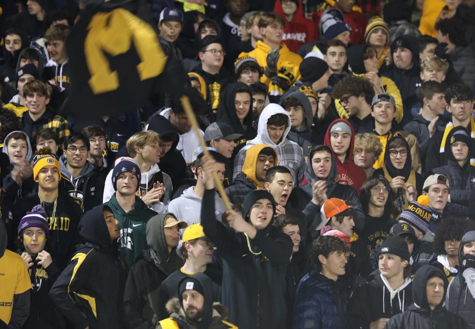 The McQuaid student section waves the school flag and cheers on the team.