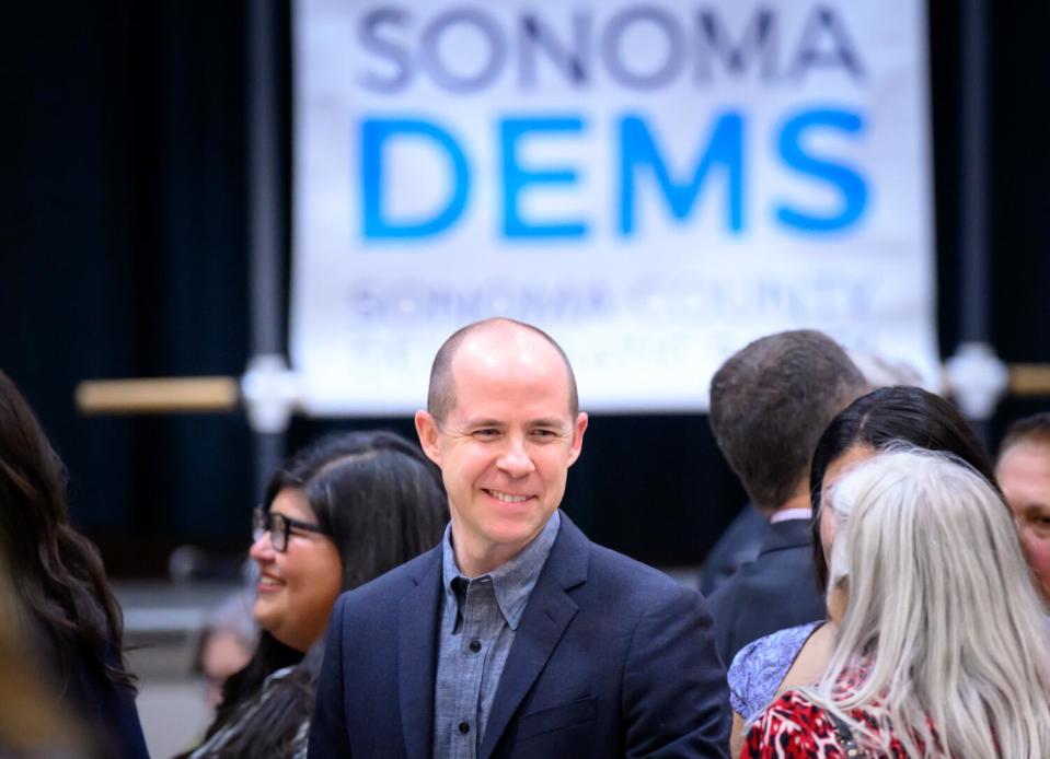 A man smiles while talking with other people.