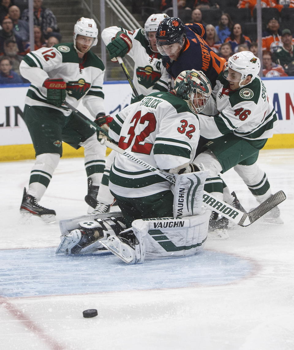 Minnesota Wild goalie Alex Stalock (32) looks for the puck after making a save, while Edmonton Oilers' Ryan Nugent-Hopkins (93) and Wild's Jared Spurgeon (46) battle in front during the second period of an NHL hockey game Friday, Feb. 21, 2020, in Edmonton, Alberta. (Jason Franson/The Canadian Press via AP)