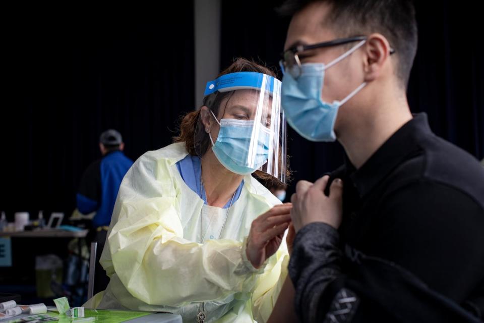 Kenny Huynh, 24, gets his first dose of the Modern COVID-19 vaccine from Dr. Rachel Spitzer at a temporary clinic for residents of Toronto’s northeast Jane and Finch neighbourhood, at the San Romanoway apartments, on Apr. 20, 2021.