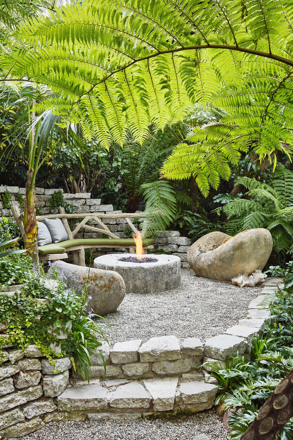 australian tree ferns drape a hidden firepit nook