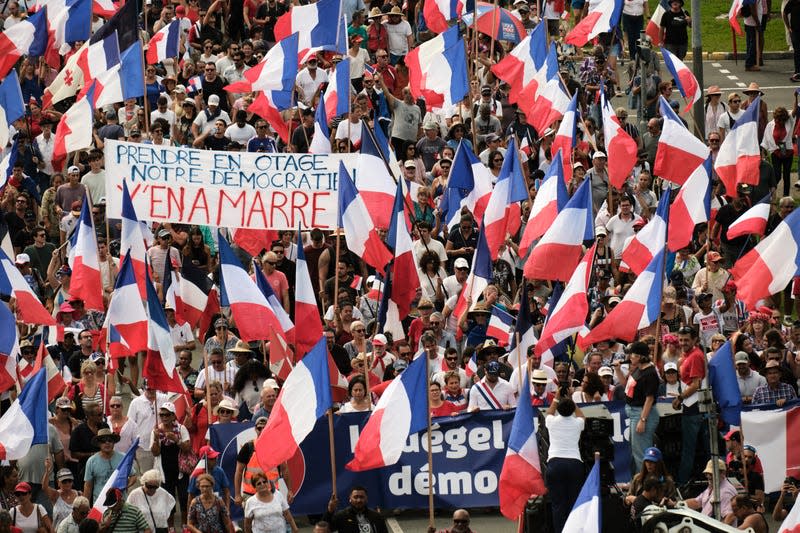 Demonstrators from several loyalist parties wave French national flags and hold a banner reading “Prendre en otage notre democratien y’en a marre” (Take our democracy away from you) as they march during a demonstration to support the enlargement of the electorate for the forthcoming provincial elections in New Caledonia, in Noumea, on April 13, 2024. - Photo: Theo Rouby / AFP (Getty Images)