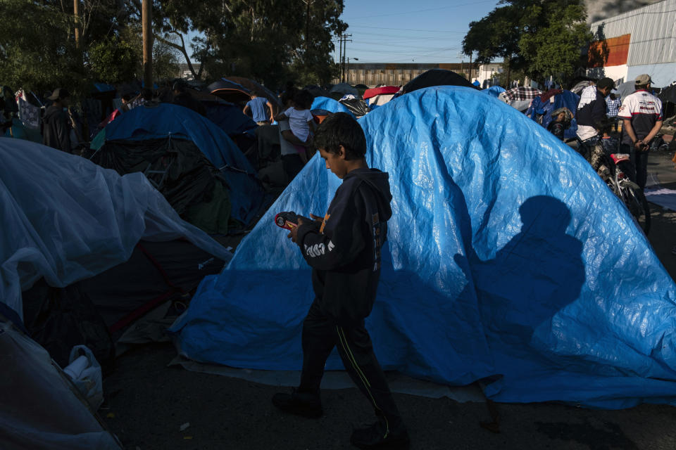 A Central American migrant boy traveling in a caravan walks among the tents of a makeshift camp against the U.S.-Mexico border fence, in a street near a closed shelter in Tijuana, Baja California state, Mexico, on Dec. 7, 2018. (Photo: Guillermo Arias/AFP/Getty Images)