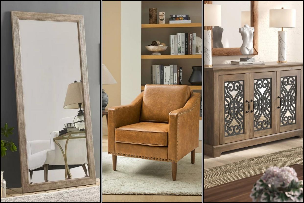 a wayfair mirror leaning against a wall, an armchair in front of a bookcase and a sideboard with lamps and decor on top of it