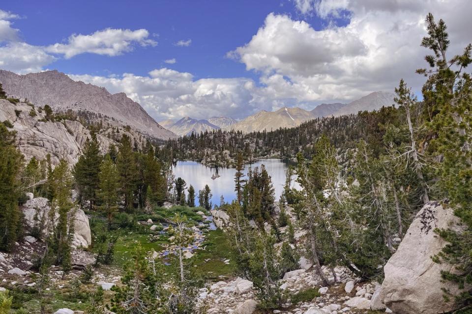 A view of a reflective lake surrounded by trees and mountains.