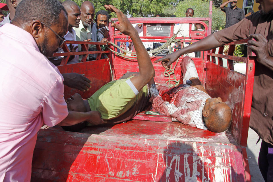 Civilians who were wounded in suicide car bomb attack are helped at check point in Mogadishu, Somalia, Saturday, Dec, 28, 2019. A police officer says a car bomb has detonated at a security checkpoint during the morning rush hour in Somalia's capital. (AP Photo/Farah Abdi Warsame)