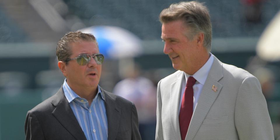 Dan Snyder and Bruce Allen speak on the field before a game in 2019.