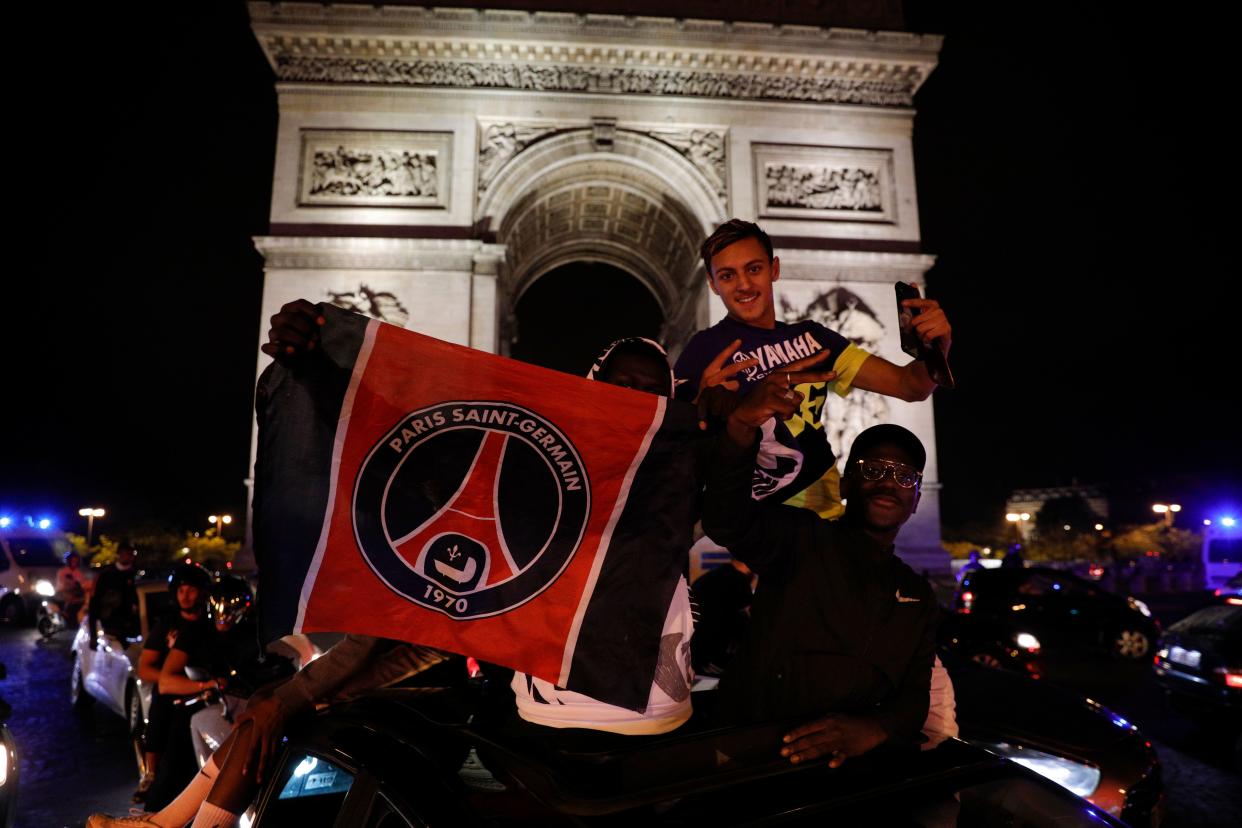 Paris Saint-Germain supporters celebrate their team's 3-0 win over RB Leipzig at the Champs-Elysees Avenue near the Arc de Triomphe in Paris on late August 18, 2020 following the UEFA Champions League semi-final football match between Leipzig and Paris Saint-Germain, played in Lisbon. - Paris Saint-Germain are through to the final of the Champions League for the first time after goals by Marquinhos, Angel Di Maria and Juan Bernat saw them ease to a 3-0 win over RB Leipzig in a one-sided semi-final in Lisbon on August 18. (Photo by GEOFFROY VAN DER HASSELT / AFP) (Photo by GEOFFROY VAN DER HASSELT/AFP via Getty Images)