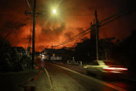 <p>A car passes as lava from a Kilauea volcano fissure illuminates the night sky, after midnight on Hawaii’s Big Island, on May 27, 2018 in Pahoa, Hawaii. (Photo: Mario Tama/Getty Images) </p>