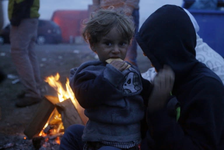 A child eats a biscuit as migrants sit around a fire near Roszke on the Hungarian-Serbian border on September 9, 2015