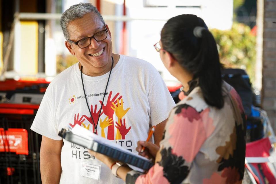 Jorge Pedroza, of Charlotte, N.C., left, a canvasser with the Hispanic Federation helps register a voter at Compare Foods in Charlotte, N.C., Tuesday, Sept. 20, 2022.