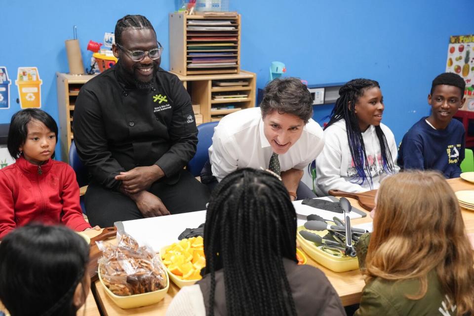 Prime Minister Justin Trudeau talks to children as he sits next to chef Jason Simpson at photo opportunity as they prepare food for a lunch program at the Boys and Girls Club East Scarborough, in Toronto, before an announcement to launch a National School Food Program, Monday, April 1, 2024. The Government is to commit $1 billion over five years with the hope that the program will deliver meals to an additional 400,000 children per year. 