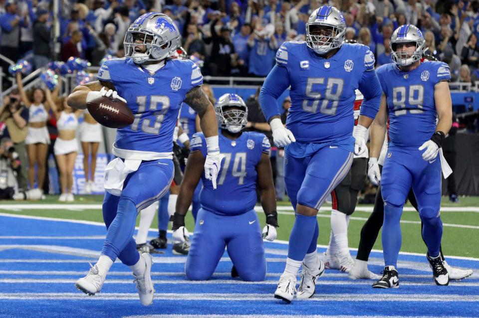 Detroit Lions' Craig Reynolds runs into the end zone for a 1-yard touchdown during the third quarter against the Tampa Bay Buccaneers in the NFC divisional round playoff game at Ford Field in Detroit on Sunday, Jan. 21, 2024. Right tackle Penei Sewell (58) celebrates.