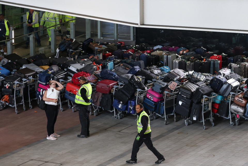 Airport workers stand next to lines of passenger luggage arranged outside Terminal 2 at Heathrow Airport in London, Britain, June 19, 2022. REUTERS/Henry Nicholls