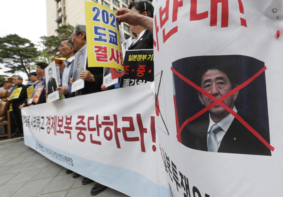 South Korean protesters with a defaced image of Japanese Prime Minister Shinzo Abe stage a rally denouncing the Japanese government's decision on their exports to South Korea in front of the Japanese Embassy in Seoul, South Korea, Tuesday, July 23, 2019. Colonial-era Korean laborers have formally registered their request with a South Korean court to get its approval for the sale of local assets of their former Japanese employer. The signs read "Stop economic retaliation." (AP Photo/Ahn Young-joon)