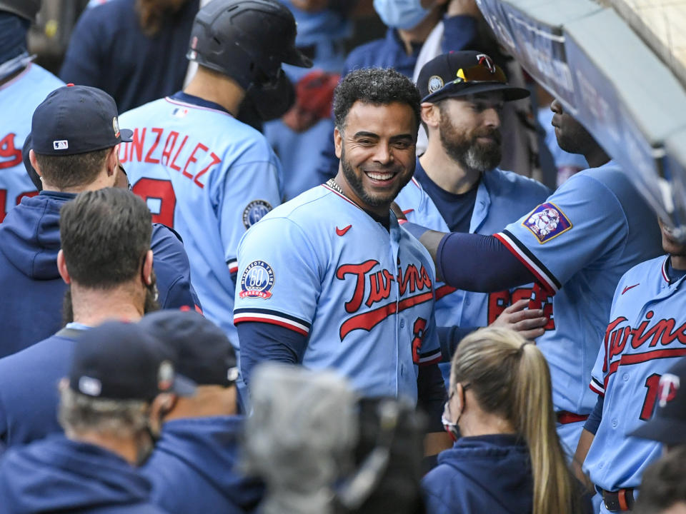 FILE - In this Sept. 27, 2020, file photo, Minnesota Twins' Nelson Cruz, center, smiles in the dugout after the Twins clinched the AL Central championship with the Chicago White Sox's loss during the tenth inning of a baseball game in Minneapolis. The Minnesota Twins are bringing back designated hitter Nelson Cruz on a one-year, $13 million contract, according to a person with knowledge of the negotiations. The agreement was reached late Tuesday and confirmed Wednesday, Feb. 3, 2021, to The Associated Press on condition of anonymity because the deal was pending completion of a physical exam.(AP Photo/Craig Lassig, File)