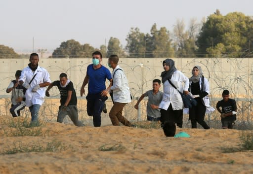 Palestinian protesters and paramedics run for cover during a demonstration at the Israel-Gaza border, in Khan Yunis in the southern Gaza Strip on August 3, 2018