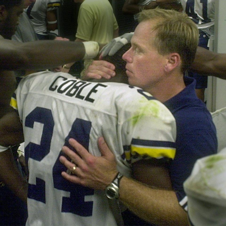 University of Akron coach Lee Owens (l) comforts cornerback Rickie Coble in the locker room after the Zips lost 28-14 to the Ohio State Buckeyes at Ohio Stadium in Columbus on Sept. 8, 2001. Coble ran back an interception for the second Akron score. (Photo: Ed Suba Jr., Akron Beacon Journal)