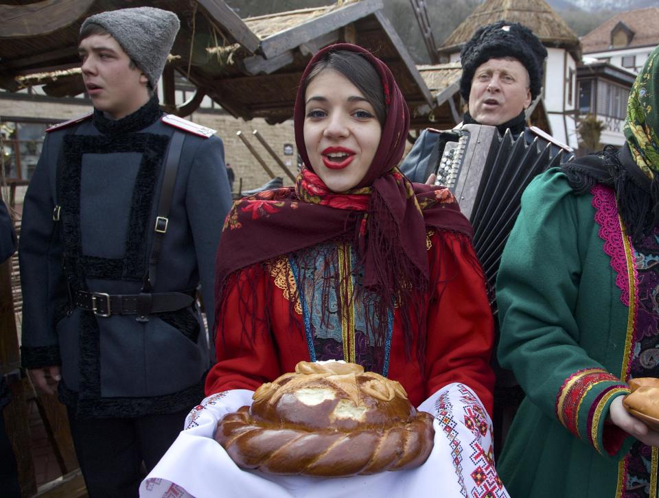 FILE - In this Feb. 6, 2013, file photo, artists dressed in folk costumes sing as they welcome guests at a street in Rosa Khutor, some 60 km east of the Black Sea resort of Sochi, Russia. Sochi has long been a choice destination for Russia's political elite. Joseph Stalin's summer residence in Zeleni Mys even features a wax mannequin of the dictator at his desk. (AP Photo/Ivan Sekretarev, file)