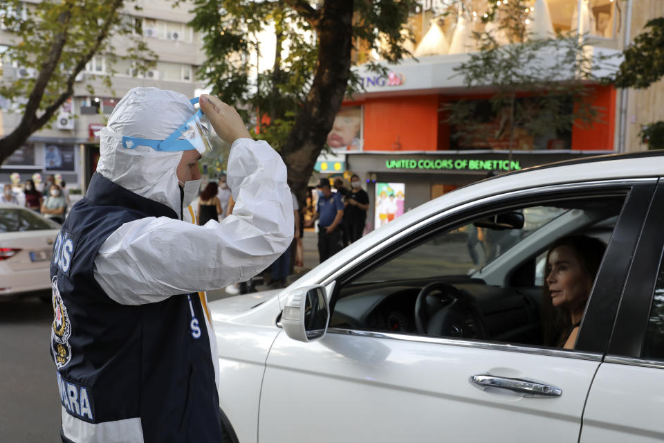 A police officer wearing a face mask to protect against the spread of coronavirus, instructs a woman to wear her mask, in Ankara, Turkey, Thursday, Aug. 6, 2020. Turkey's interior ministry announced new measures Wednesday to curb the spread of COVID-19 as daily confirmed cases peaked above 1,000. (AP Photo/Burhan Ozbilici)