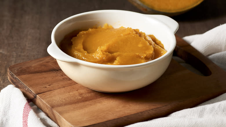 Reduced pumpkin puree in bowl on cutting board