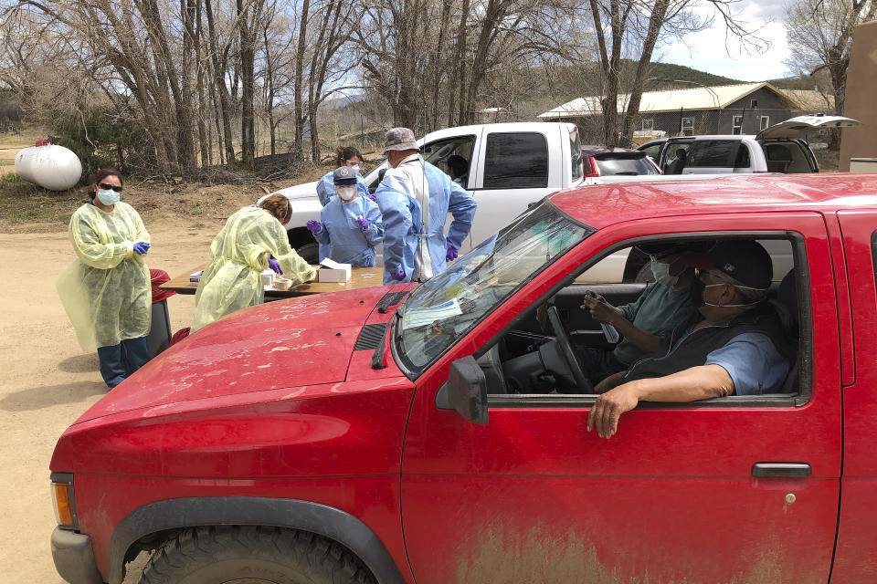 Brothers Matthew Allrunner, driving pickup truck, and Ed Allrunner, passenger, attend testing for the coronavirus by the state Health Department and Indian Health Service at the Native American community of Picuris Pueblo, N.M., Thursday, April 23, 2020. Small Native American pueblo tribes across New Mexico are embracing extraordinary social distancing measures that include guarded roadblocks and universal testing for the coronavirus in efforts to insulate themselves from a contagion with frightening echoes of the past. (AP Photo/Morgan Lee)