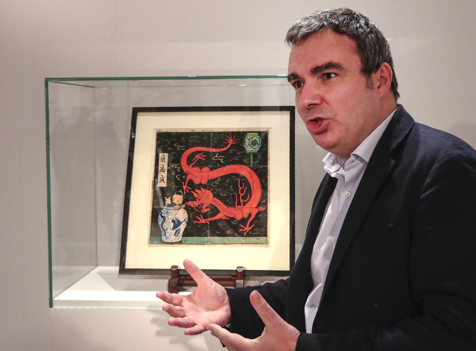 Art expert Eric Leroy gestures as he talks to the Associated-Press during an interview as he stands next to the inked and water-painted original panel of the comic character Tintin from the 1936 "The Blue Lotus" album drawn by Belgian creator Herge, is displayed at the Artcurial auction house in Paris, Wednesday, Jan. 13, 2021. The art work with an estimates value of 2.2 to 2.8 million euros (US $ 2.6 to 3.4 million), is going on sale Thursday. (AP Photo/Michel Euler)