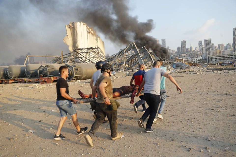 Civilians carry a person at the explosion scene that hit the seaport, in Beirut Lebanon, Tuesday, Aug. 4, 2020. (AP Photo/Hussein Malla)