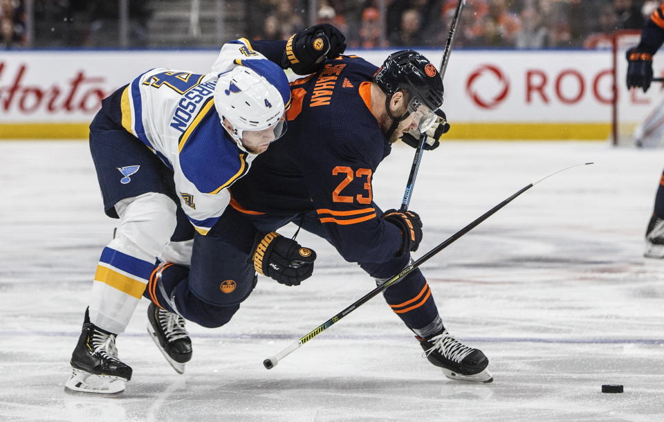 St. Louis Blues' Carl Gunnarsson (4) and Edmonton Oilers' Riley Sheahan (23) compete for the puck during the second period of an NHL hockey game Friday, Jan. 31, 2020, in Edmonton, Alberta. (Jason Franson/The Canadian Press via AP)