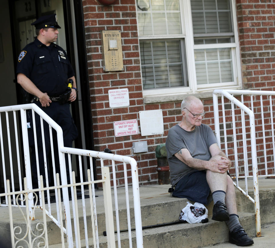 James Shields, Sr., right, sits in front of the building where his son and others were killed in the Queens borough of New York, Tuesday, July 31, 2018. Police said the murder-suicide that left at least four people dead in New York City, may have stemmed from a trans-Atlantic custody fight. (AP Photo/Seth Wenig)