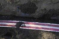 Tape warning that electrical lines are buried below is rolled out as a Pacific Gas and Electric crew works on burying power lines in Vacaville, Calif., Wednesday, Oct. 11, 2023. PG&E wants to bury many of its power lines in areas threatened by wildfires. (AP Photo/Jeff Chiu)