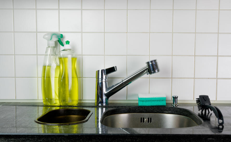 Bottles of dishwashing detergent next to a sink.