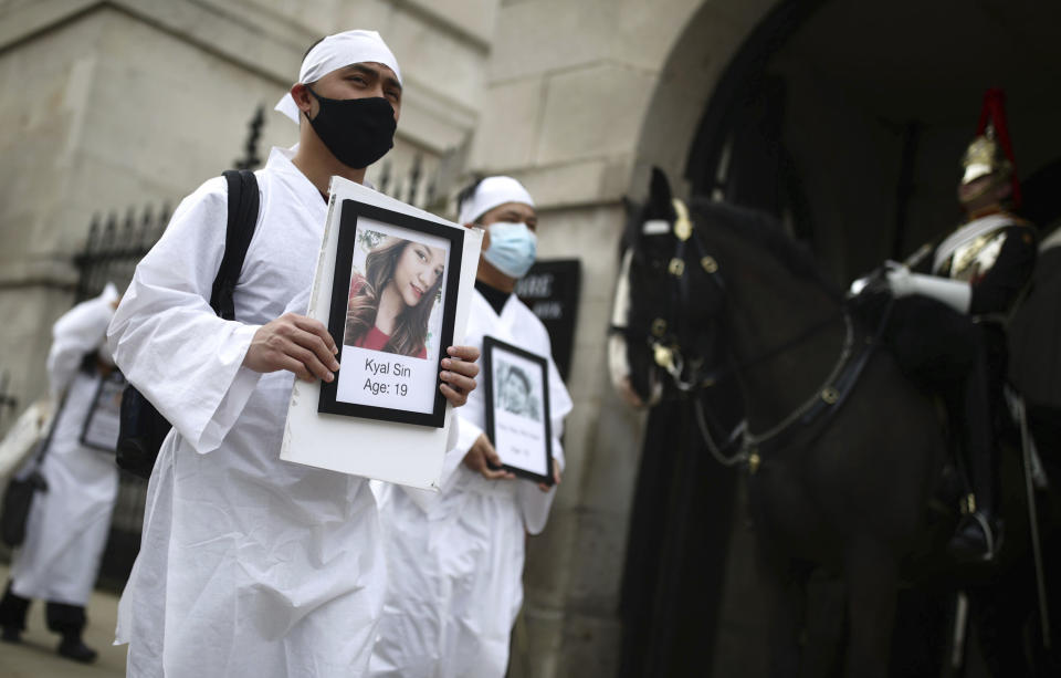 Protesters holding photos of protestors killed, as they march in Westminster, demonstrating against the Feb. 1 coup in Myanmar which ousted Aung San Suu Kyi's elected government, in London, Wednesday, March 31, 2021. (Aaron Chown/PA via AP)