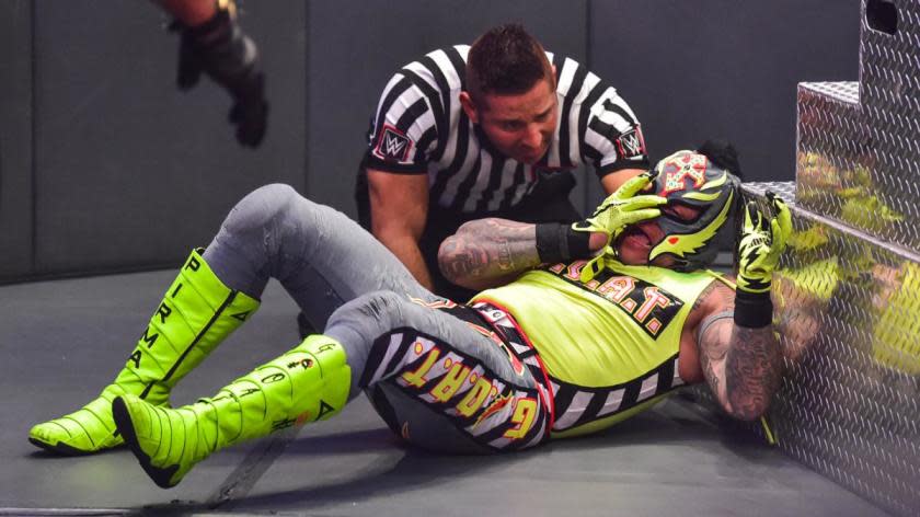The ref checks on Rey Mysterio, who hopes to keep his eye in place.