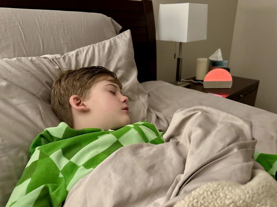 a boy sleeping in a bed with an alarm clock
