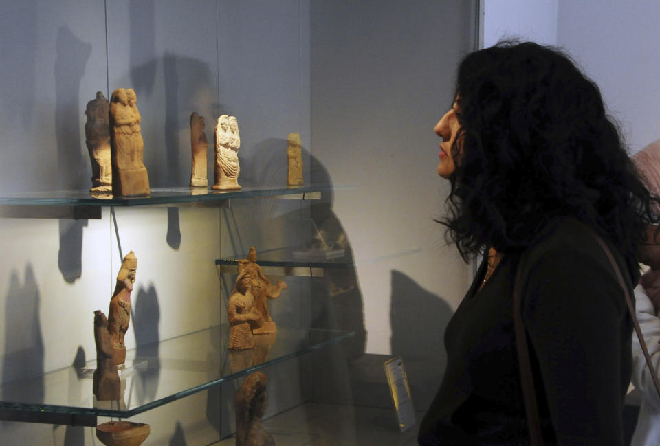 In this photo released by the Syrian official news agency SANA, a visitor looks at ancient artifacts during the reopening ceremony for Syria's National Museum, in Damascus, Syria, Sunday, Oct. 28, 2018. Syrian officials, foreign archeologists and restoration specialists attended the Sunday reopening ceremony in the heart of Damascus more than six years after the prominent institution was shut down and emptied as the country's civil war encroached on the capital. (SANA via AP)