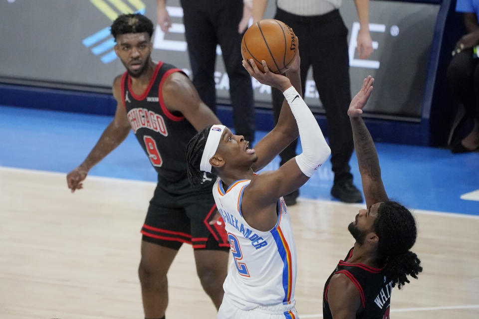 Oklahoma City Thunder guard Shai Gilgeous-Alexander (2) shoots between Chicago Bulls forward Patrick Williams (9) and guard Coby White, right, during the second half of an NBA basketball game Friday, Jan. 15, 2021, in Oklahoma City. (AP Photo/Sue Ogrocki)