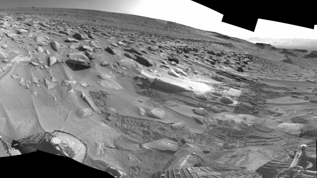  black and white view of a martian landscape littered with sand dunes and large rocks 