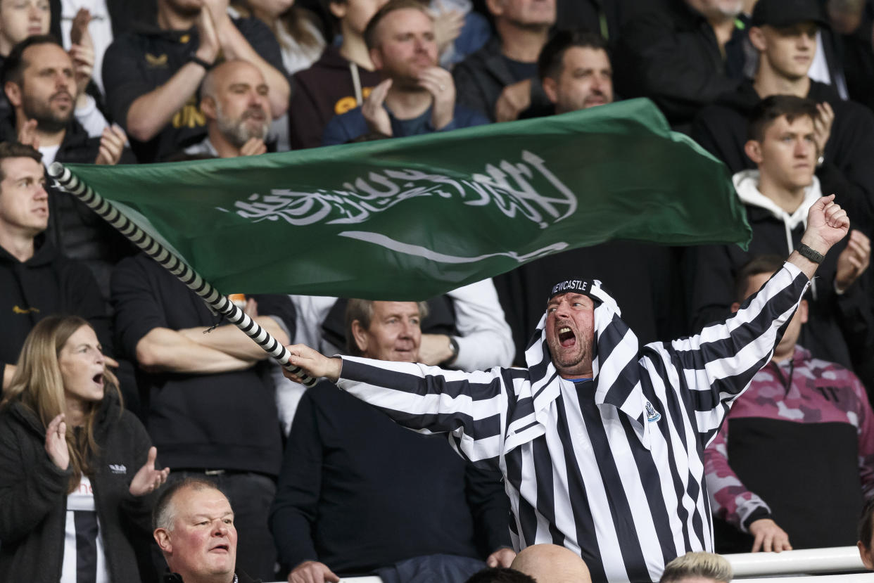 A Newcastle United fan waves a Saudi Arabian flag.