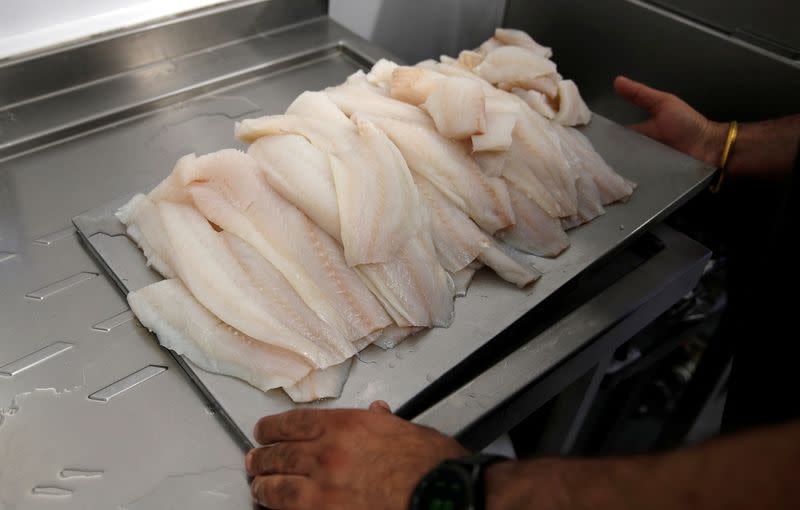 Owner of Hooked Fish and Chips shop, Bally Singh, carries prepared fish fillets at his take-away in West Drayton